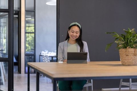 Asian Woman in Modern Office Using Tablet Smiling