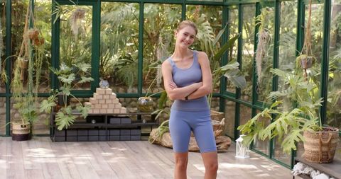 Woman in Yoga Outfit Relaxing in Greenhouse Surrounded by Plants