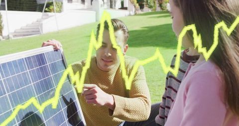 Man demonstrating solar panel technology to child with neon energy graph overlay on lawn