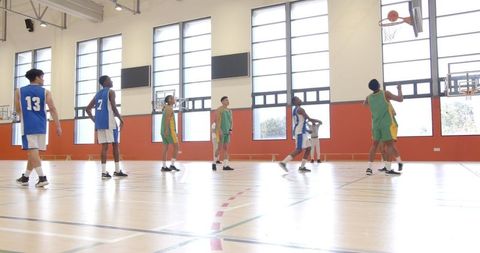 Basketball Players Active on Indoor Court in Intense Game