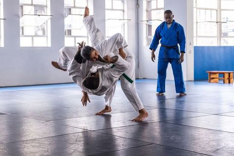 Diverse judo class practicing throws in dojo