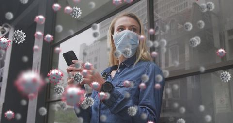 Masked woman using smartphone with digital virus overlay