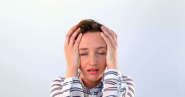 Stressed caucasian casual businesswoman with eyes closed holding head on grey background. Communication, confusion and business, unaltered.