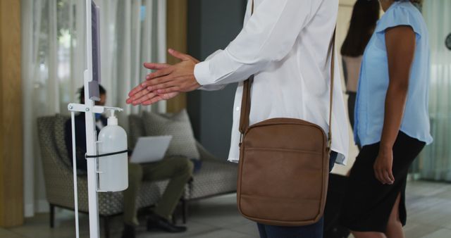 Man Sanitizing Hands at Office Entrance - Download Free Stock Images Pikwizard.com