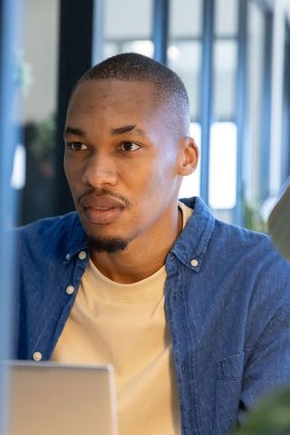 African american professional working on laptop in modern office, focused headshot