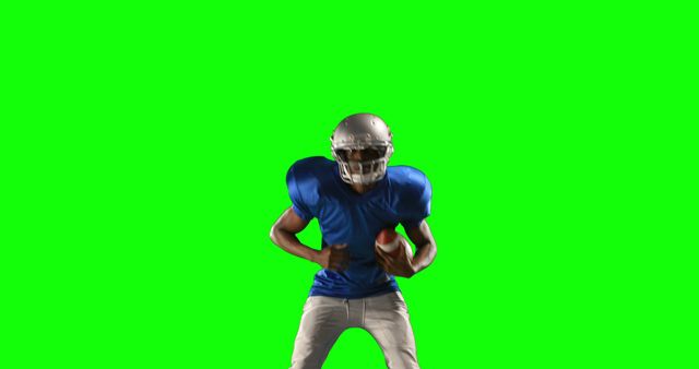 The image features an African American football player wearing a helmet and holding a football, set against a green screen backdrop. This high-quality stock image can be effectively used for sports-themed presentations, advertisements, and promotional materials focusing on football, athleticism, or team dynamics. It is also ideal for creating visually engaging content for sports magazines, magazines and sports blogs, and online articles that discuss big-game events, sports training, and football strategy.