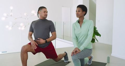 Diverse Pair Lunging on Yoga Mats in Bright Fitness Studio