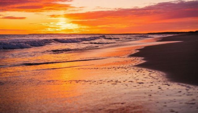 Sunset glow reflecting on wet sand along empty ocean shoreline