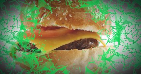 Closeup cheeseburger featuring melted cheddar, tomato, sesame bun with green graphic overlay