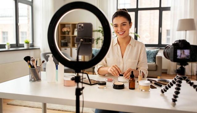 Beauty vlogger filming makeup tutorial with ring light in cozy living room home studio