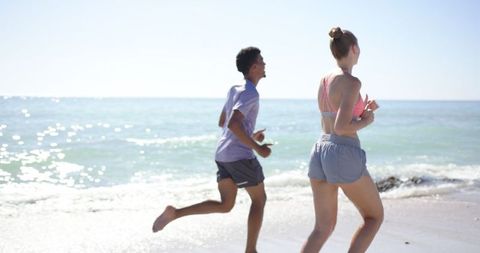 Active Couple Jogging on Sunny Beach in Athletic Wear