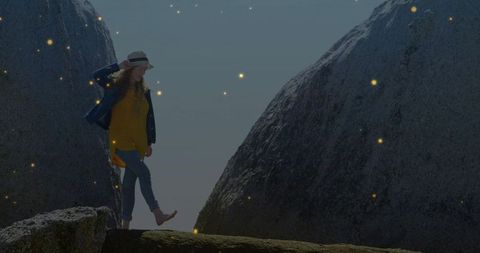 Woman balancing on rocky ledge amid massive boulders