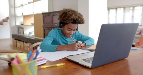 Boy Wearing Headphones Studying Online at Home