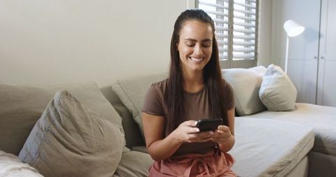 Woman Relaxing on Sofa Using Smartphone in Modern Living Room