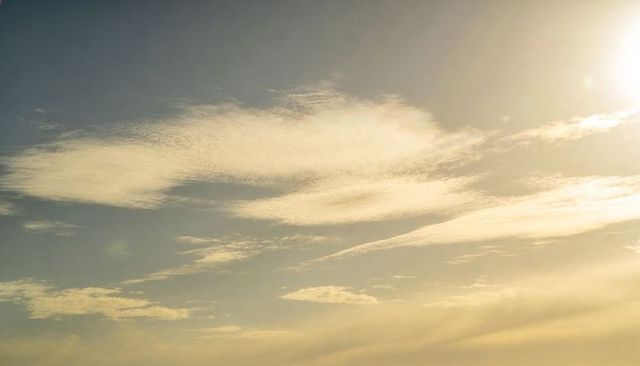 Golden late-afternoon sky with wispy cirrus and streaky stratus, sun flare and soft gradient