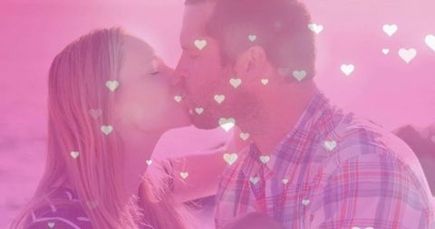 Mid adult couple kissing with romantic heart overlays