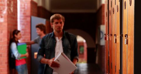 College student walking towards lockers in university hallway