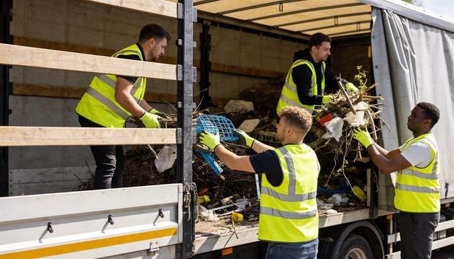 Municipal crew loading branches and litter into curtain-sided truck during cleanup