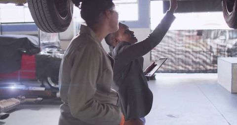 Women Collaborating on Vehicle Inspection in Industrial Garage