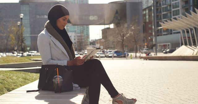 Woman in hijab working in urban park on tablet - Download Free Stock Images Pikwizard.com