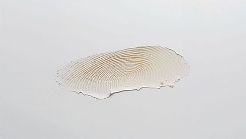 Displaying thin beige fingerprint impression with central whorl on neutral gray surface