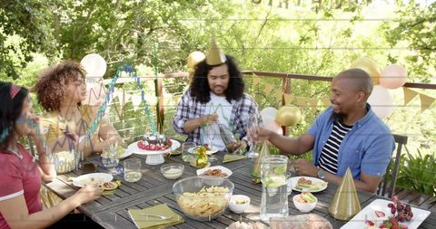 Friends celebrating on deck pouring drinks and sharing cake at outdoor birthday party