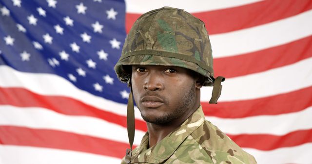 Depicts an African American soldier wearing a camouflaged uniform and helmet, standing in front of an American flag. Perfect for themes related to military service, patriotism, national pride, and honoring veterans. Suitable for use in articles, advertisements, educational materials, and social media posts highlighting military appreciation, recruiting efforts, or commemorative events.