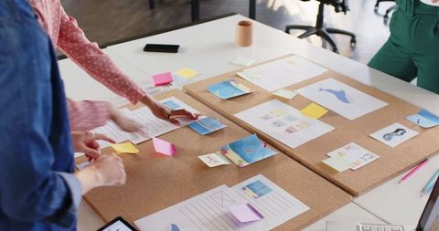 Team of Female Creative Professionals Organizing Project Ideas on Corkboard