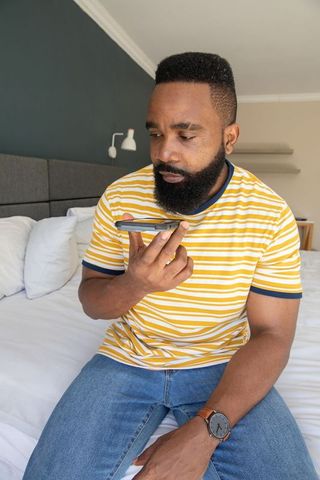 Mid adult man using smartphone in modern bedroom setting