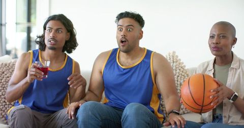 African american friends watching basketball game at home reacting with shock and joy