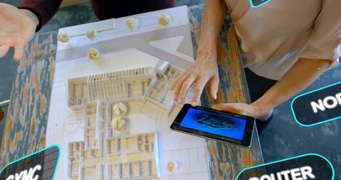 Designers examining architectural scale model with tablet showing 3d rendering
