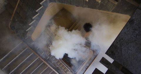 Person with Flare Walking in Smoky Stairwell