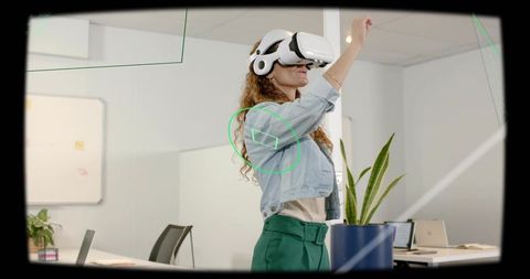 Mature woman using VR headset in modern office interacting with holographic HUD