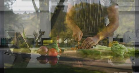 Home cook slicing carrots in modern kitchen with tablet