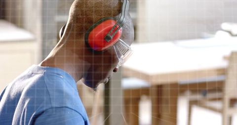 Woodworker working at bench wearing red earmuffs and safety glasses