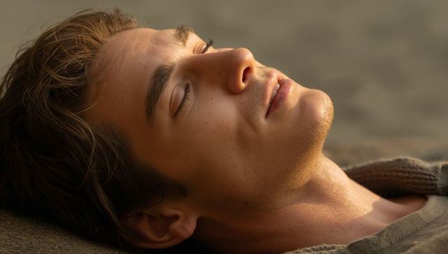 Young man reclining with eyes closed soaking up golden hour soft light and calm expression