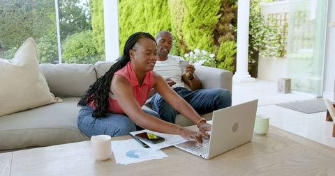 Couple Collaborating on Project at Home with Laptop and Documents
