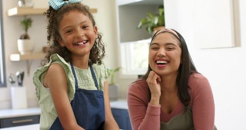 Smiling Multicultural Mother and Daughter Cooking Together in Bright Modern Home Kitchen