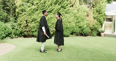 Graduating couple celebrating success with diplomas outdoors