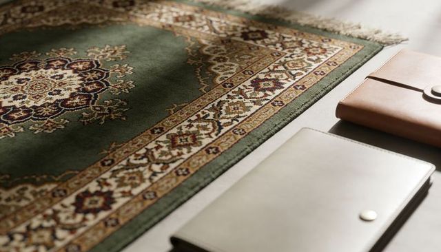 Ornate green persian-style rug medallion with leather notebooks and soft sunlight