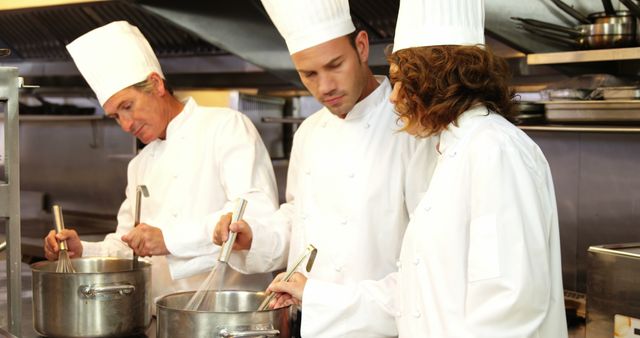 Professional chefs working together in a restaurant kitchen, focusing on cooking and food preparation. The chefs are wearing traditional white uniforms and chef hats. Useful for content related to culinary arts, professional cooking, fine dining restaurants, teamwork in the kitchen, or chef training programs.