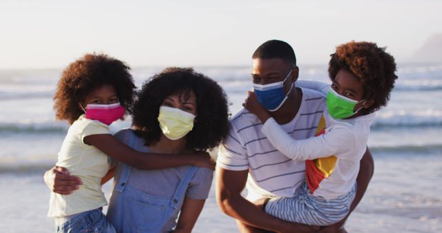 Family spending quality time together on a beach vacation, all wearing face masks for safety. Perfect for articles about family travel, safe vacations during health concerns, and promoting protective measures while enjoying outdoor activities.