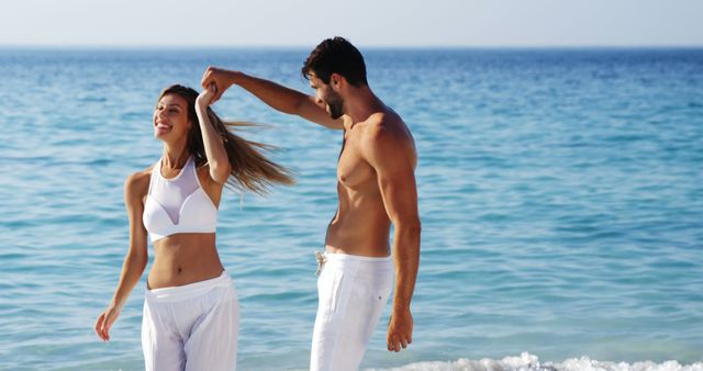 Romantic caucasian couple having fun, holding hands and dancing in the sun at beach, copy space. Romance, relationship, summer, lifestyle and vacations, unaltered.