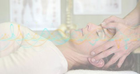 Woman receiving cranial manual therapy with therapist cradling head and waveform overlay