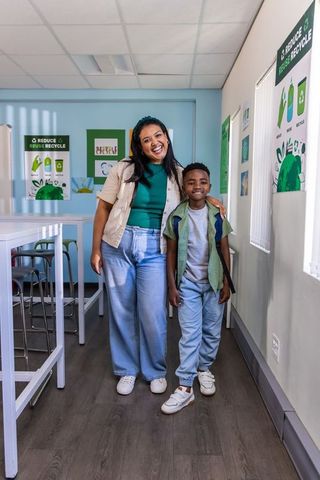 Mentoring moment: woman and student smiling and standing in classroom promoting recycling