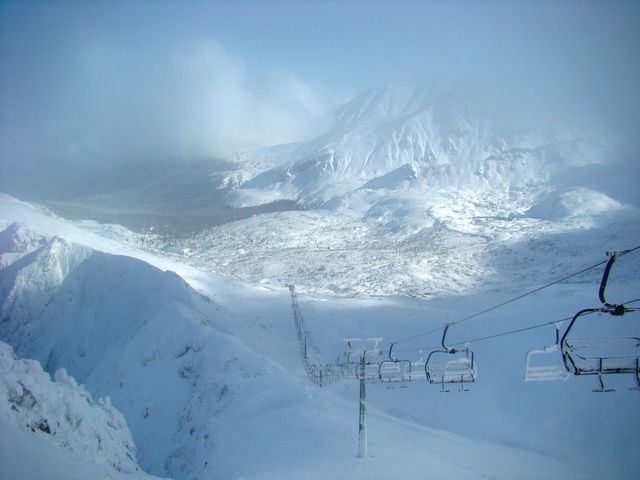A breathtaking view of a snow-covered mountain landscape featuring a ski lift emerging from the thick snow. Ideal for winter sports campaigns, travel brochures, adventure magazines, and scenic advertising focusing on winter tourism. Perfect for use in content involving snowboarding, skiing, or winter vacations.