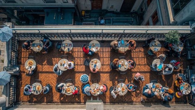 Sunlit rooftop cafe aerial view dining and socializing on wooden terrace during brunch
