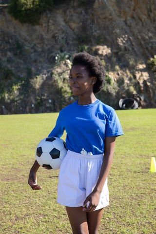 Teenage soccer athlete holding ball on field