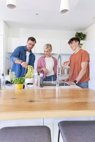 Family cooking at modern kitchen island with pull-down faucet and wooden countertop