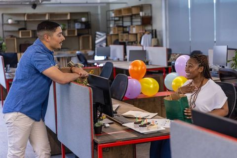 Coworkers celebrating in office with gifts and balloons